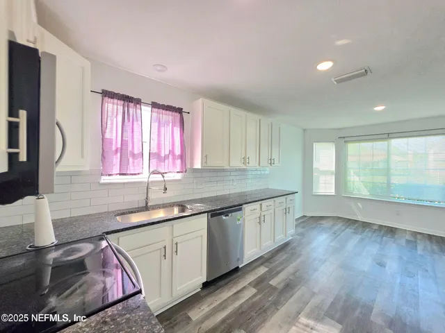 a kitchen with a sink wooden floor and a large window