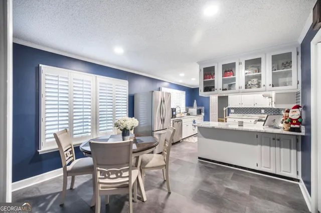 a kitchen with a dining table chairs and large window