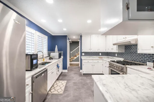 a large kitchen with a stove top oven a sink a counter space and cabinets