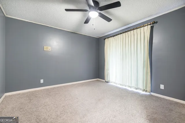 an empty room with windows and fan