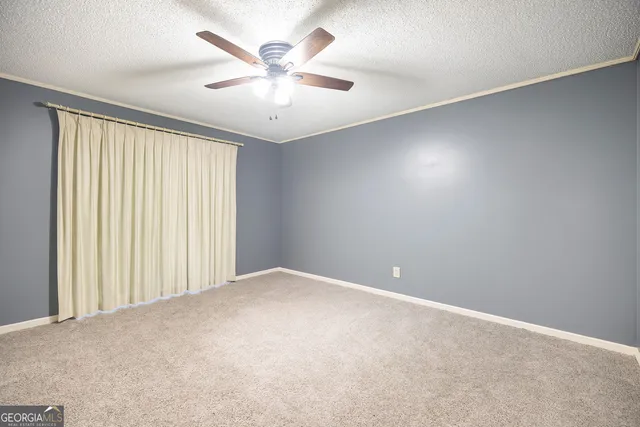 an empty room with windows and fan