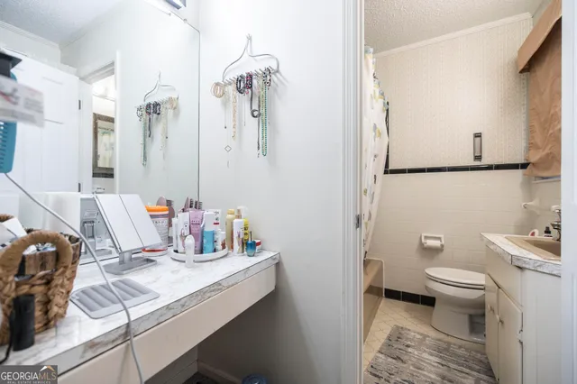 a bathroom with a granite countertop sink a toilet and a shower curtain