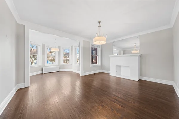 an empty room with wooden floor fireplace and windows