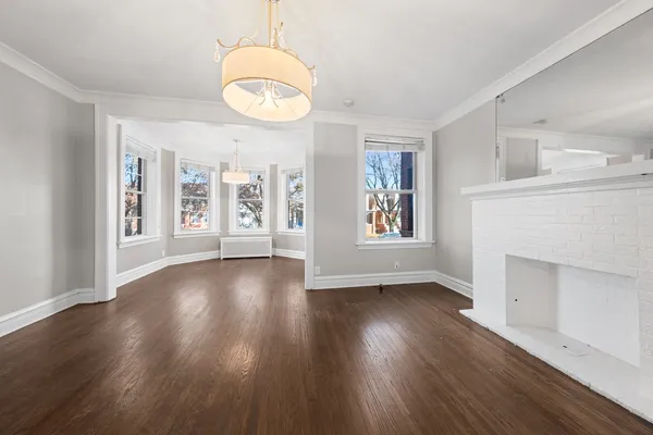 a view of an empty room with wooden floor and windows