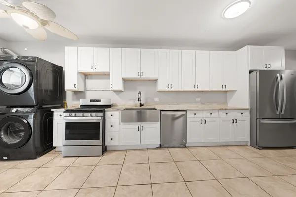 a kitchen with stainless steel appliances granite countertop a sink a stove a washer and dryer