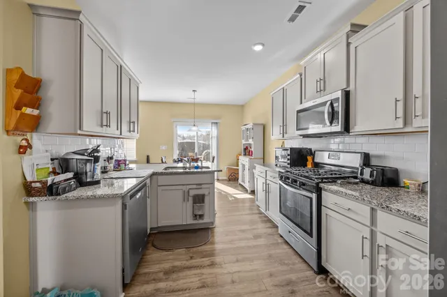 a kitchen with stainless steel appliances granite countertop a stove top oven a sink dishwasher and a refrigerator