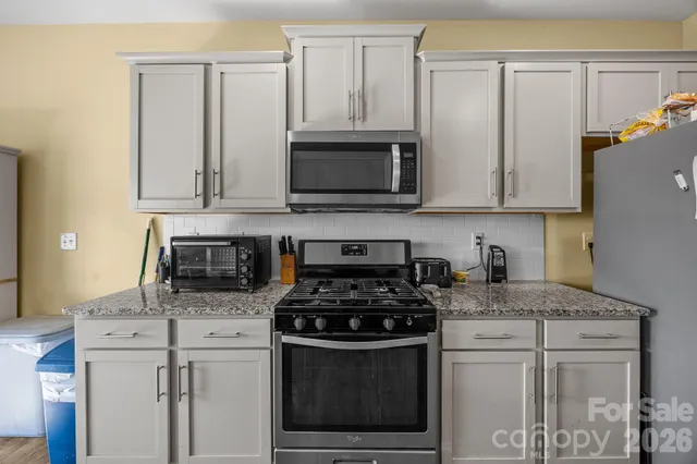 a kitchen with granite countertop white cabinets and black appliances