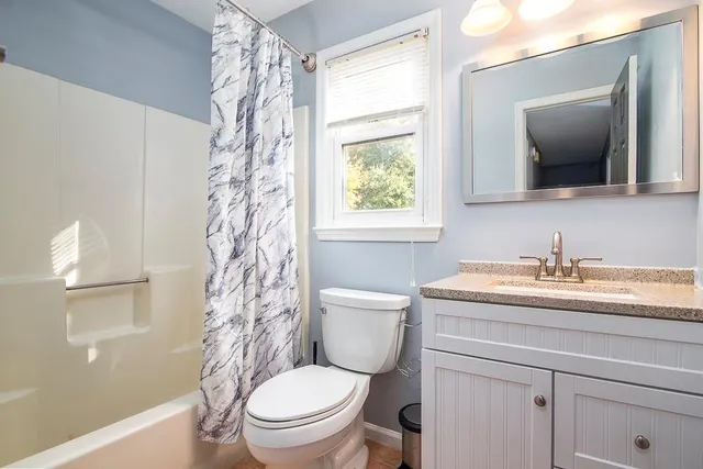 a bathroom with a granite countertop toilet a sink a mirror a and a window