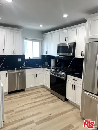 a kitchen with granite countertop a refrigerator and a stove top oven