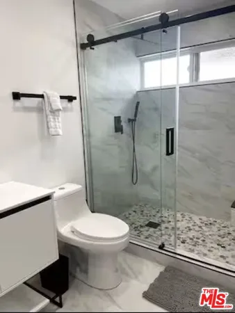 a white toilet sitting next to a shower