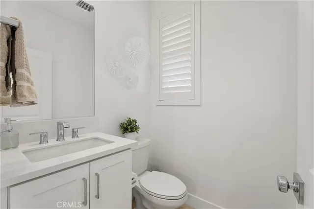 a bathroom with a granite countertop toilet sink and mirror
