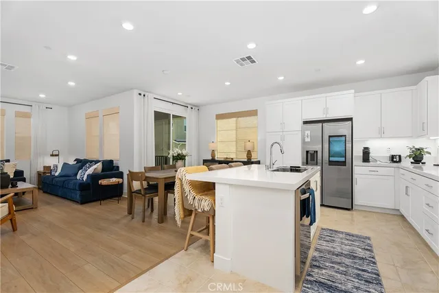 a kitchen that has a lot of cabinets a sink a stove and chairs in it