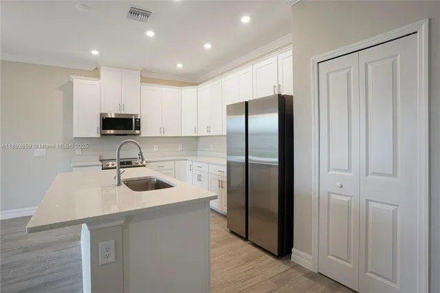 a kitchen with stainless steel appliances granite countertop a refrigerator a sink and a stove top oven