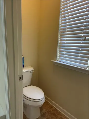 a white toilet sitting next to a small window