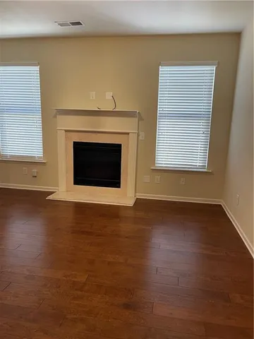 a view of an empty room with wooden floor and a fireplace