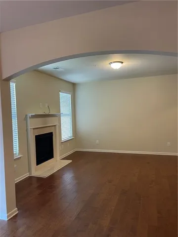 a view of an empty room with wooden floor fireplace and a window