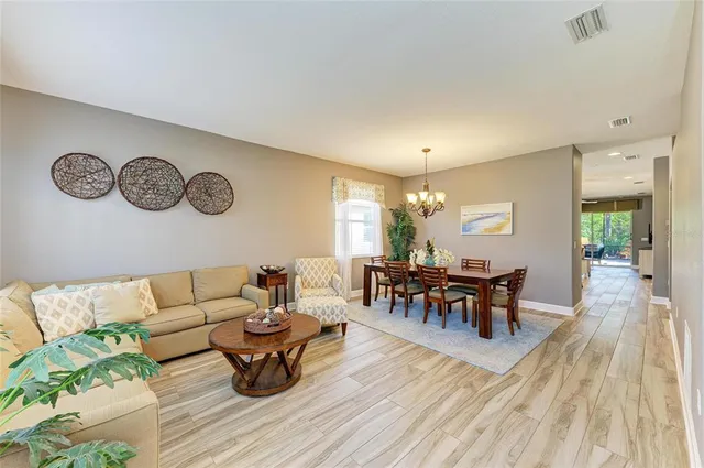 a kitchen with stainless steel appliances granite countertop a refrigerator a sink dishwasher a dining table and chairs with wooden floor