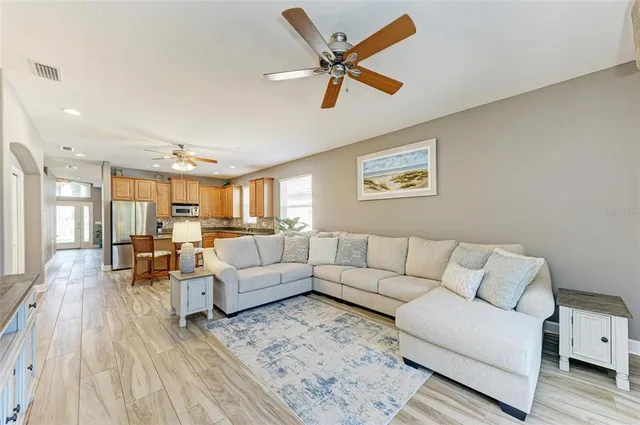 a kitchen with stainless steel appliances granite countertop a refrigerator a sink dishwasher a stove and a dining table with wooden floor