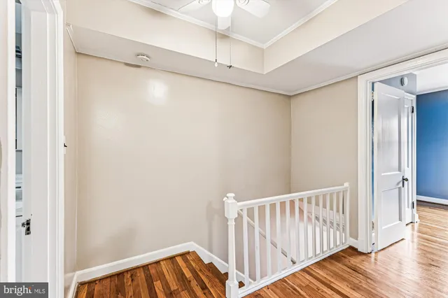 a view of a hallway with wooden floor and a bathroom