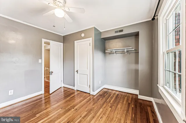 a view of empty room with wooden floor and fan