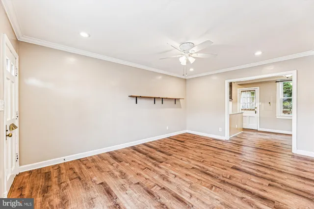 a view of empty room with wooden floor and ceiling fan