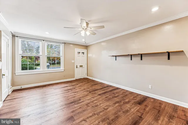 a view of an empty room with a window and wooden floor