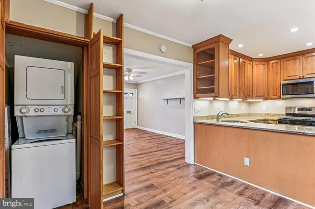 a kitchen with stainless steel appliances granite countertop a refrigerator a stove and a sink with wooden floor