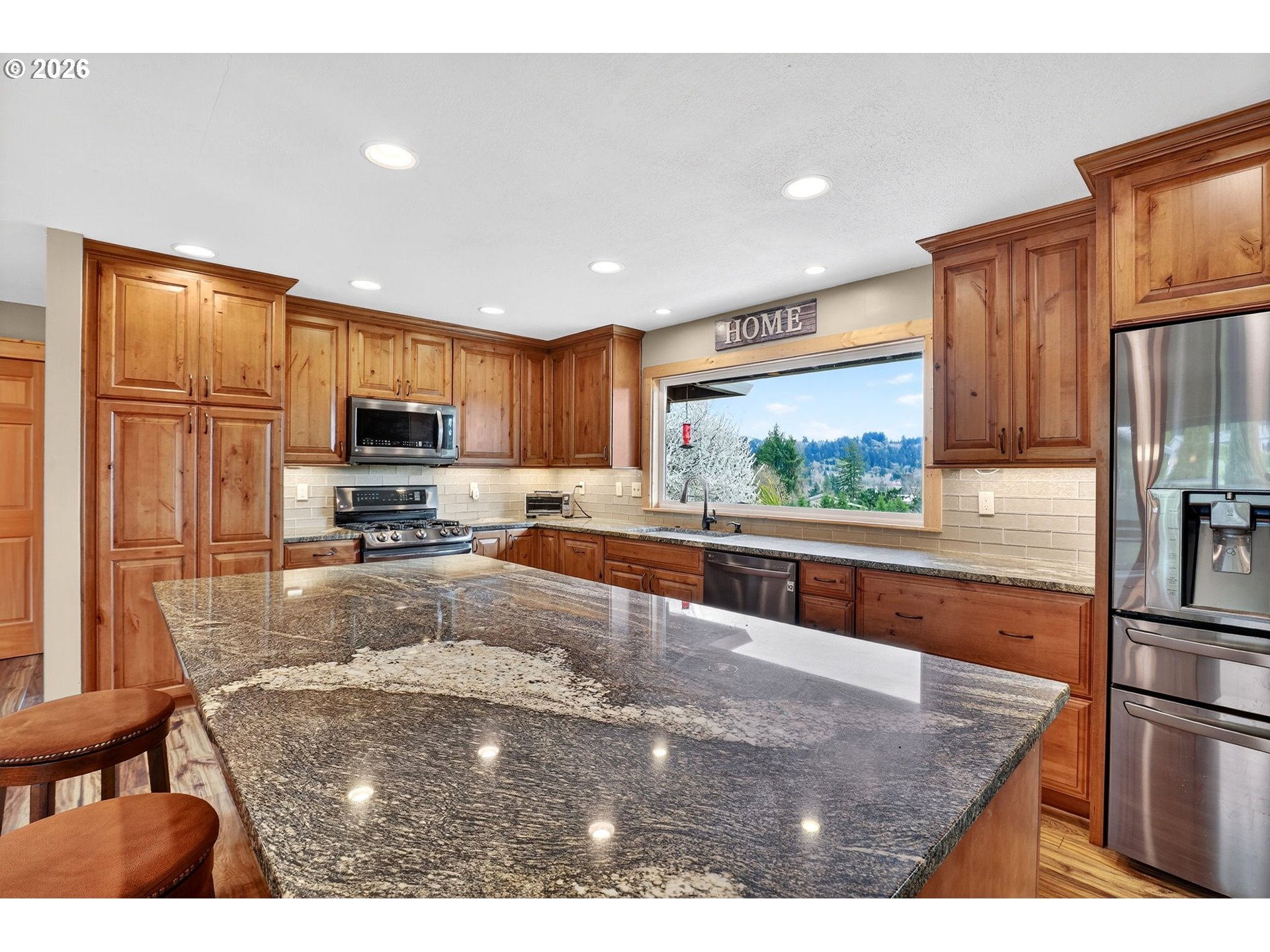 9732 Southeast Ladera Court Damascus, OR 97089 - Photo 11 of 41 a kitchen with stainless steel appliances granite countertop a refrigerator a stove top oven and a sink with wooden floor