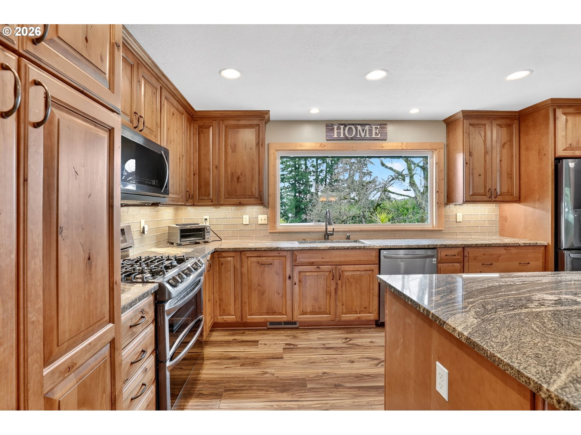 9732 Southeast Ladera Court Damascus, OR 97089 - Photo 6 of 41 a kitchen with stainless steel appliances granite countertop a stove a sink and a microwave