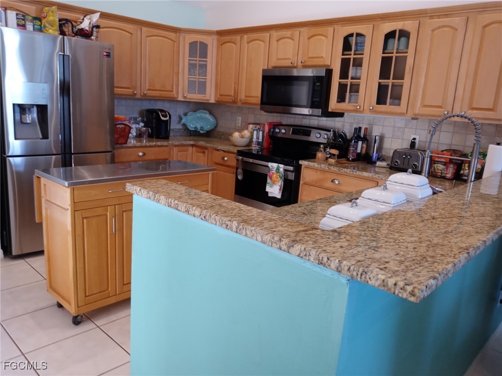 3184 Stringfellow Road St. James City, FL 33956 - Photo 41 of 46 a kitchen with stainless steel appliances granite countertop a sink stove refrigerator and microwave