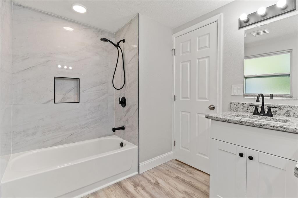 2716 Berdetta Street Leesburg, FL 34748 - Photo 12 of 35 a bathroom with a granite countertop sink a mirror and a bathtub