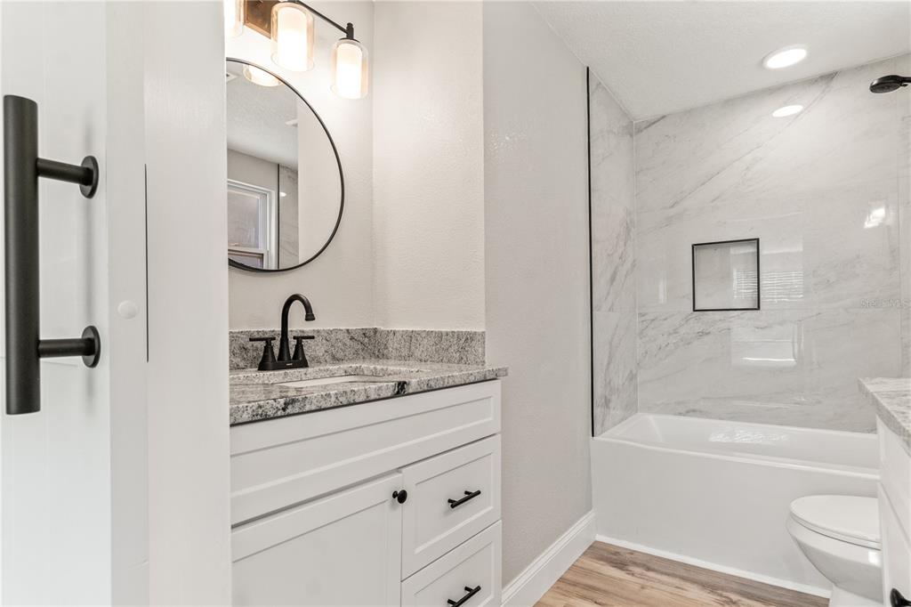 2716 Berdetta Street Leesburg, FL 34748 - Photo 13 of 35 a bathroom with a granite countertop sink a toilet and a bathtub