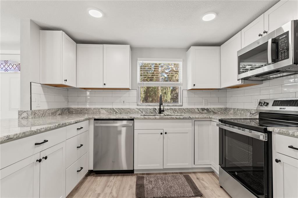 2716 Berdetta Street Leesburg, FL 34748 - Photo 4 of 35 a kitchen with stainless steel appliances granite countertop a sink and stove top oven