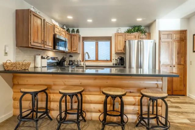 a kitchen with stainless steel appliances granite countertop a table chairs sink and cabinets