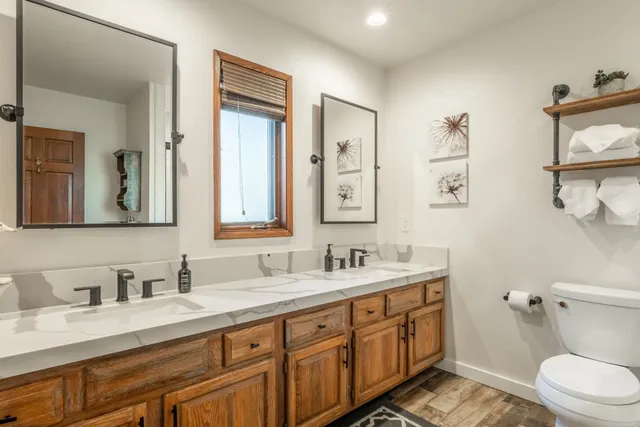 a bathroom with double vanity sink a mirror and a toilet