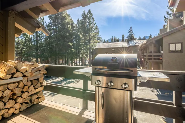 a view of a patio with table and chairs under an umbrella with large trees