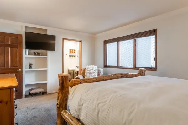 a bed room with a bed television and a large window