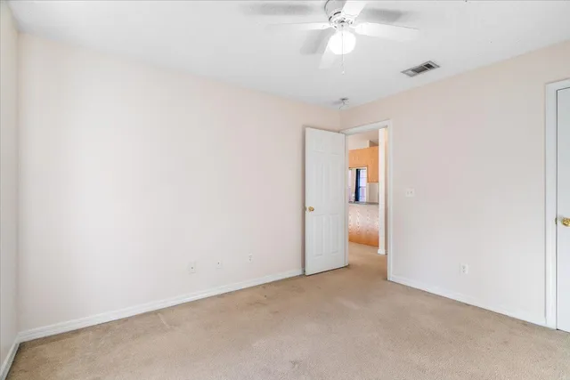 an empty room with an entryway and chandelier fan