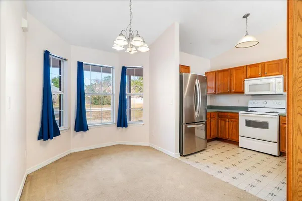 a kitchen with stainless steel appliances granite countertop a refrigerator a stove a sink dishwasher a oven with white cabinets and wooden floor