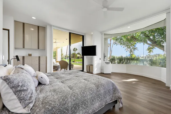 a bedroom with a large bed and a flat tv screen on dresser