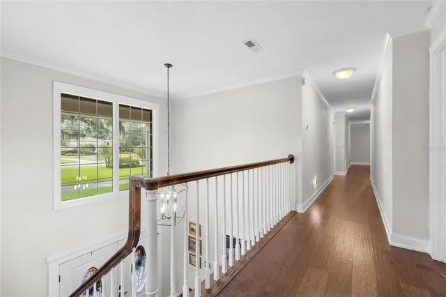 a view of a hallway with wooden floor and windows