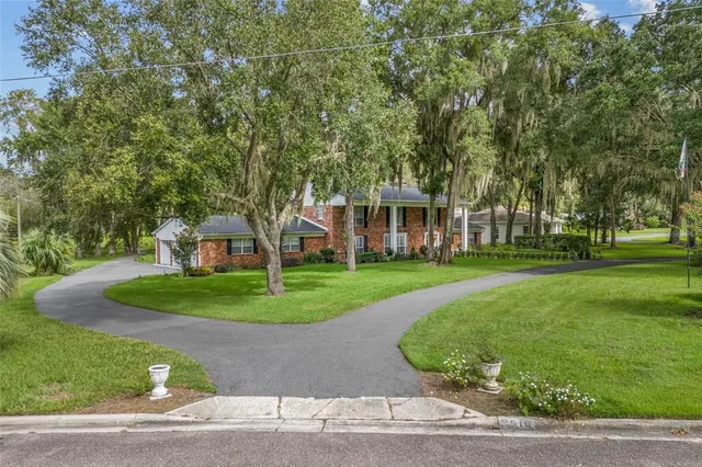 a view of a big house with a big yard and large trees