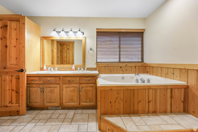 605 North Loafer Canyon Road Elk Ridge, UT 84651 - Photo 9 of 53 Bathroom with double vanity, a jetted tub and cabin style wood finishes.