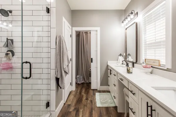 a bathroom with a double vanity sink a toilet a mirror and shower