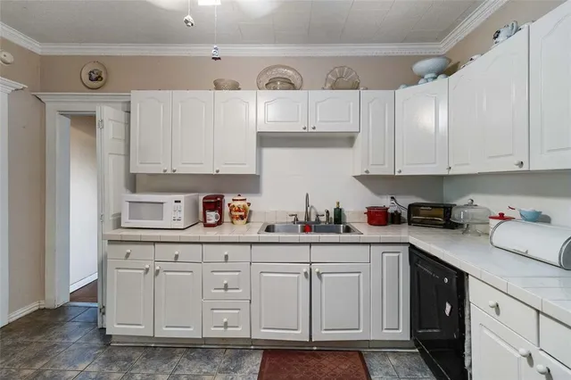 a kitchen with white cabinets and sink