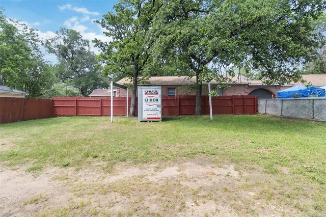 a view of a house with a yard and large tree