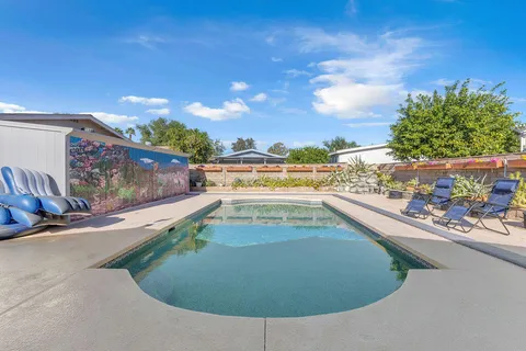 a kitchen with stainless steel appliances kitchen island granite countertop a refrigerator a stove a dining table and chairs with wooden floor