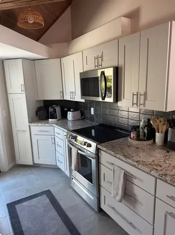 a kitchen with stainless steel appliances granite countertop a stove a sink and a microwave