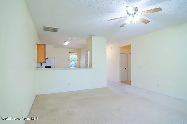 an empty room with a chandelier fan and windows