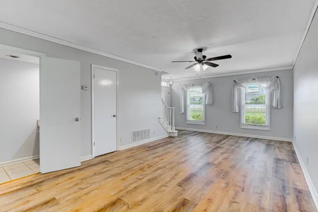 a view of empty room with wooden floor and fan